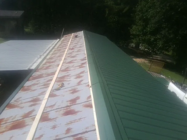 Old rusted panels beside newly installed green metal roofing — Wind Damage Roof Repair by Roofing Brothers in Atwood