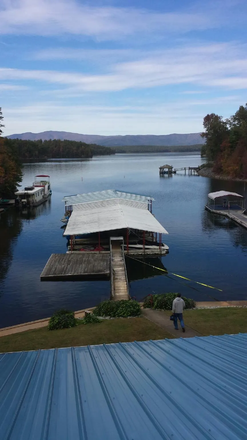 View across a lake from a newly installed blue metal roof in Atwood